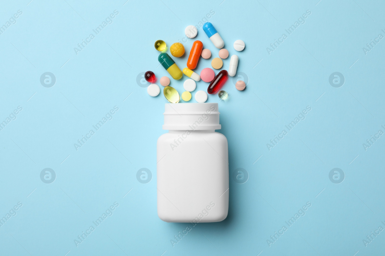 Photo of Bottle and scattered pills on color background, top view