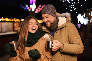 Happy couple with mulled wine at winter fair