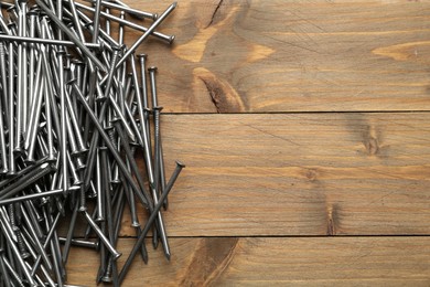 Photo of Many metal nails on wooden background, flat lay. Space for text