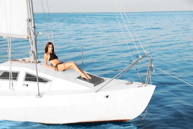 Beautiful woman in bikini relaxing on yacht during sea trip