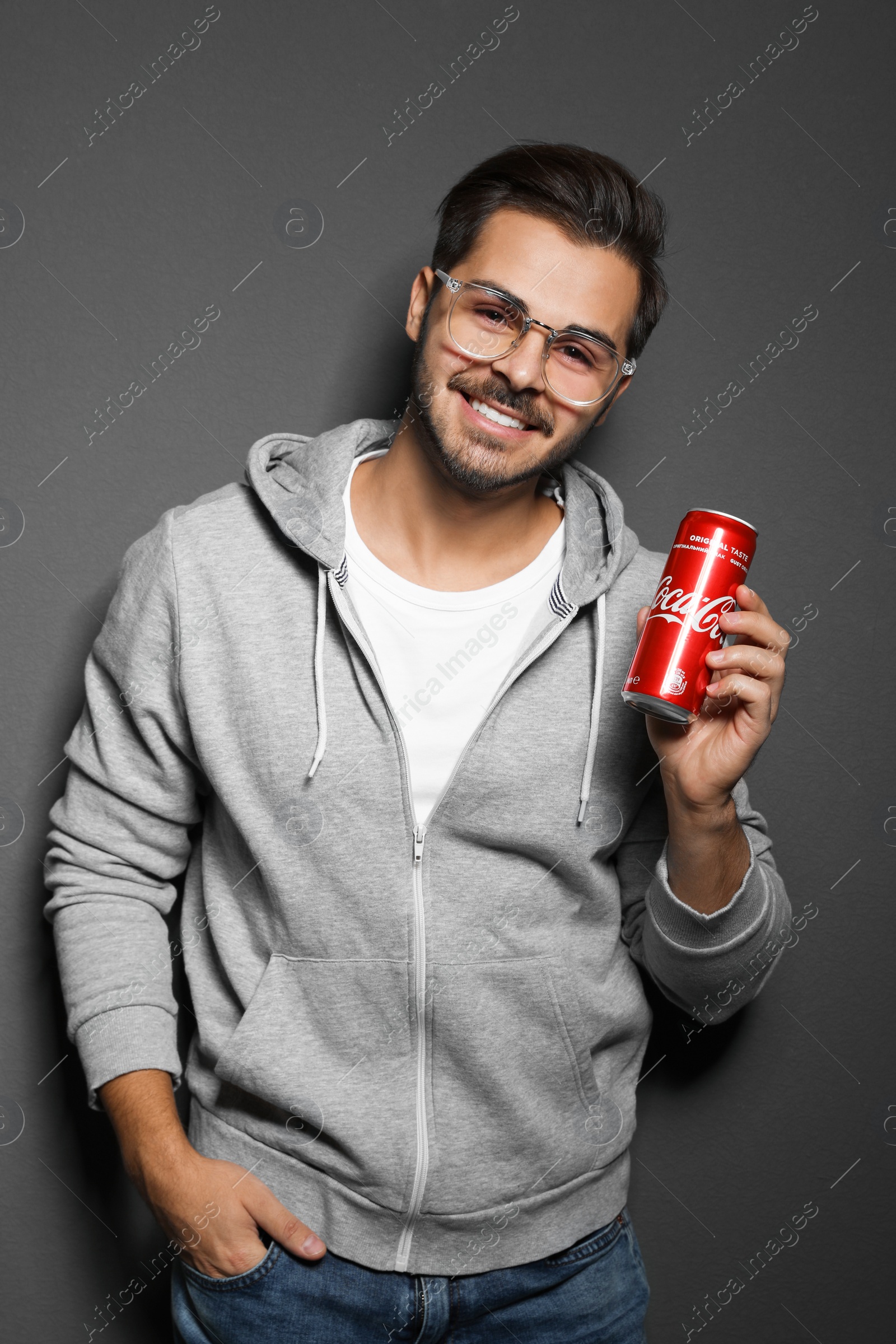 Photo of MYKOLAIV, UKRAINE - NOVEMBER 28, 2018: Young man with Coca-Cola can on dark background