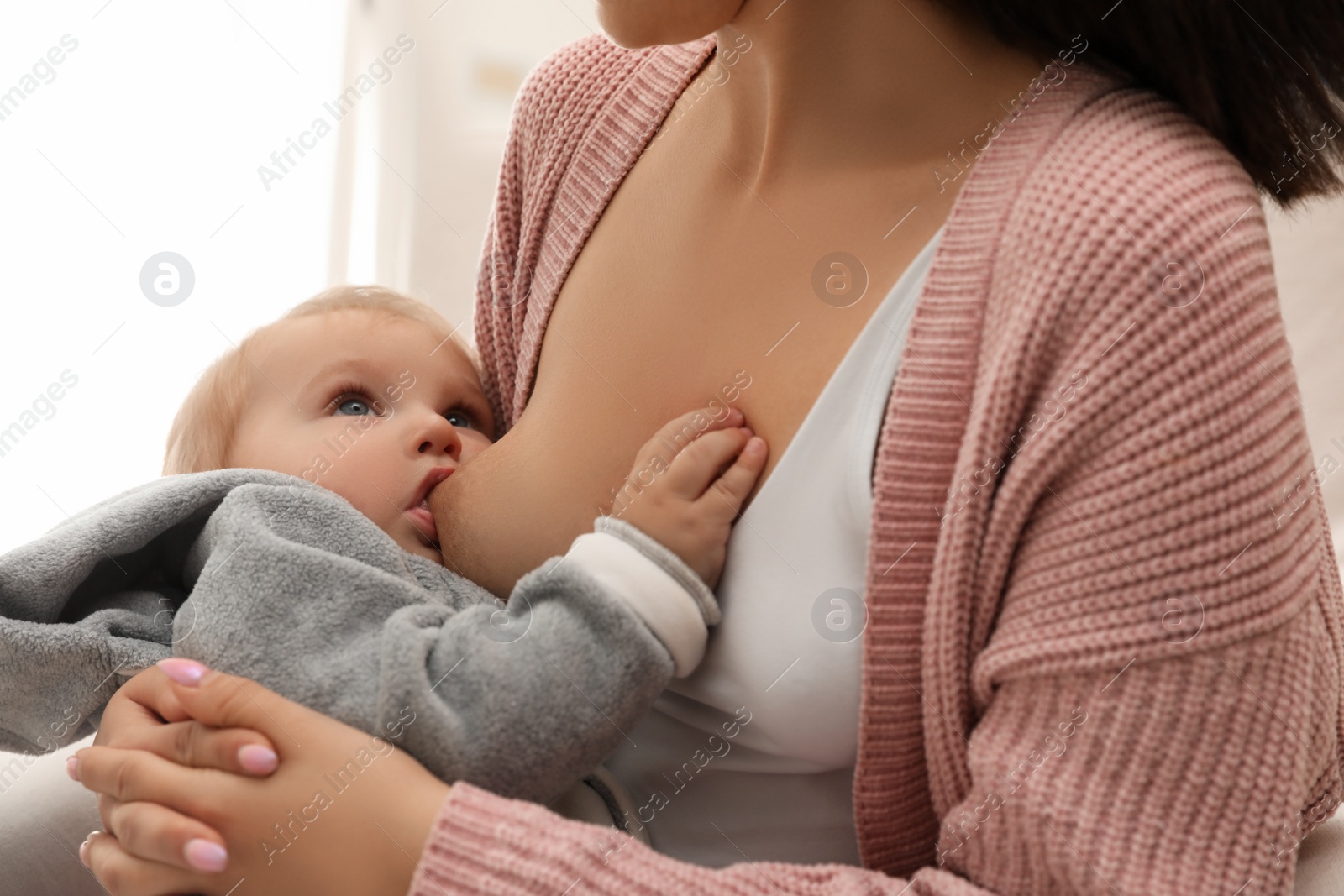 Photo of Woman breastfeeding her little baby at home, closeup