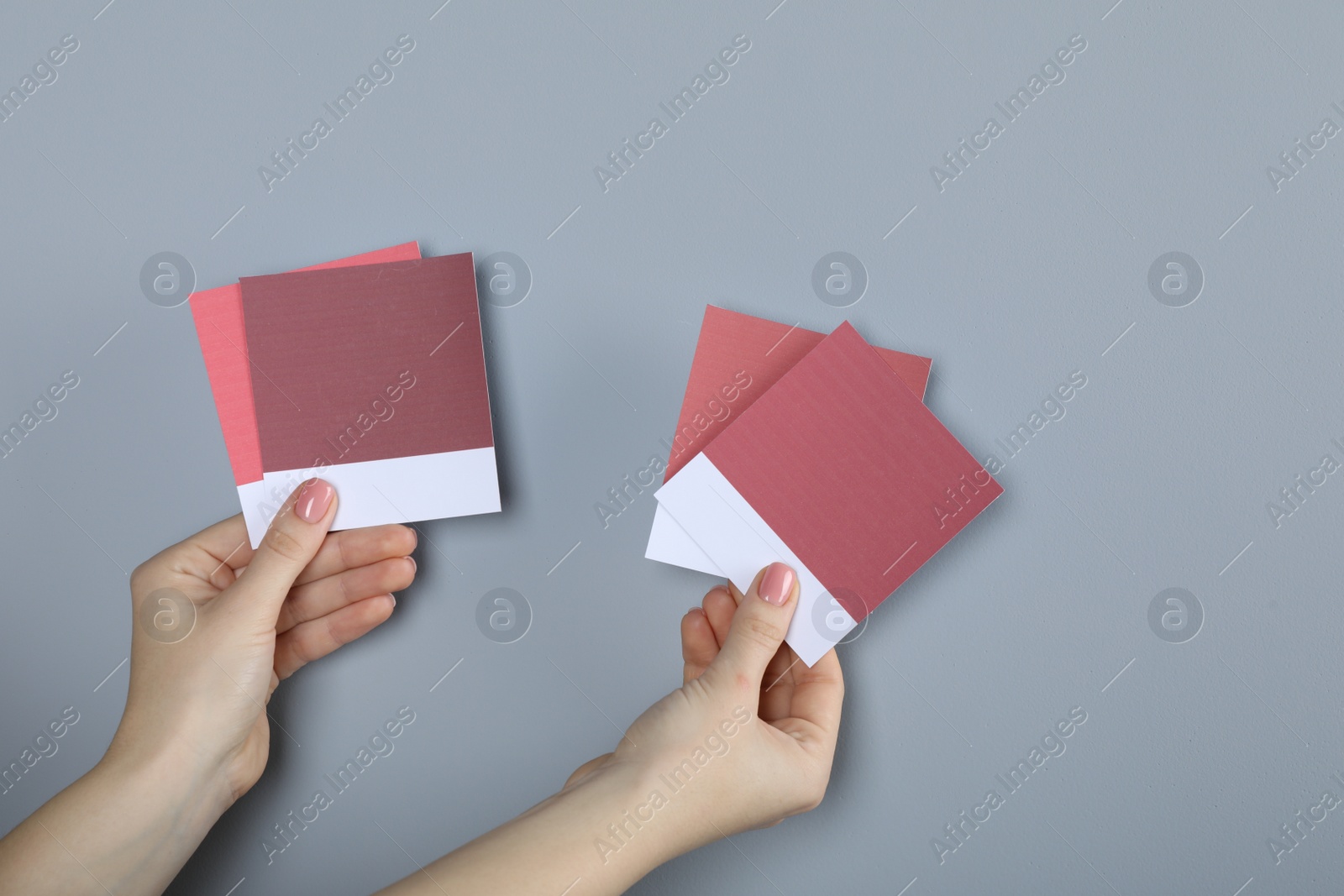 Photo of Woman with color sample cards choosing paint shade near grey wall, closeup. Interior design