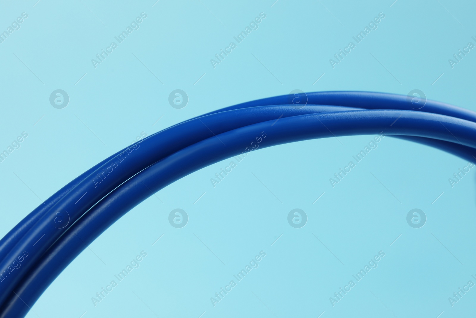 Photo of Many electrical cables on light blue background, closeup