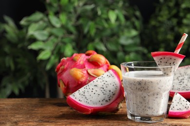 Photo of Delicious pitahaya smoothie and fresh fruits on wooden table, space for text