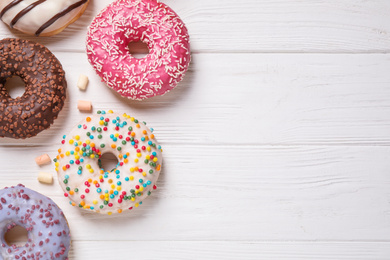 Yummy donuts and space for text on white wooden background, flat lay