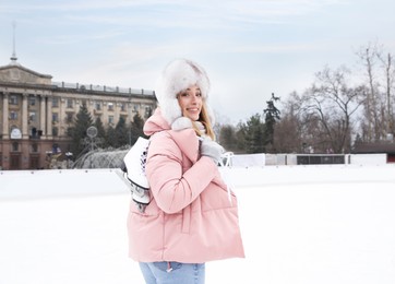 Image of Woman with figure skates near ice rink outdoors. Space for text