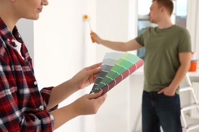 Couple with paint chips choosing new wall color in apartment during repair, closeup
