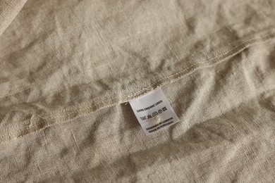 Clothing label on beige garment, closeup view