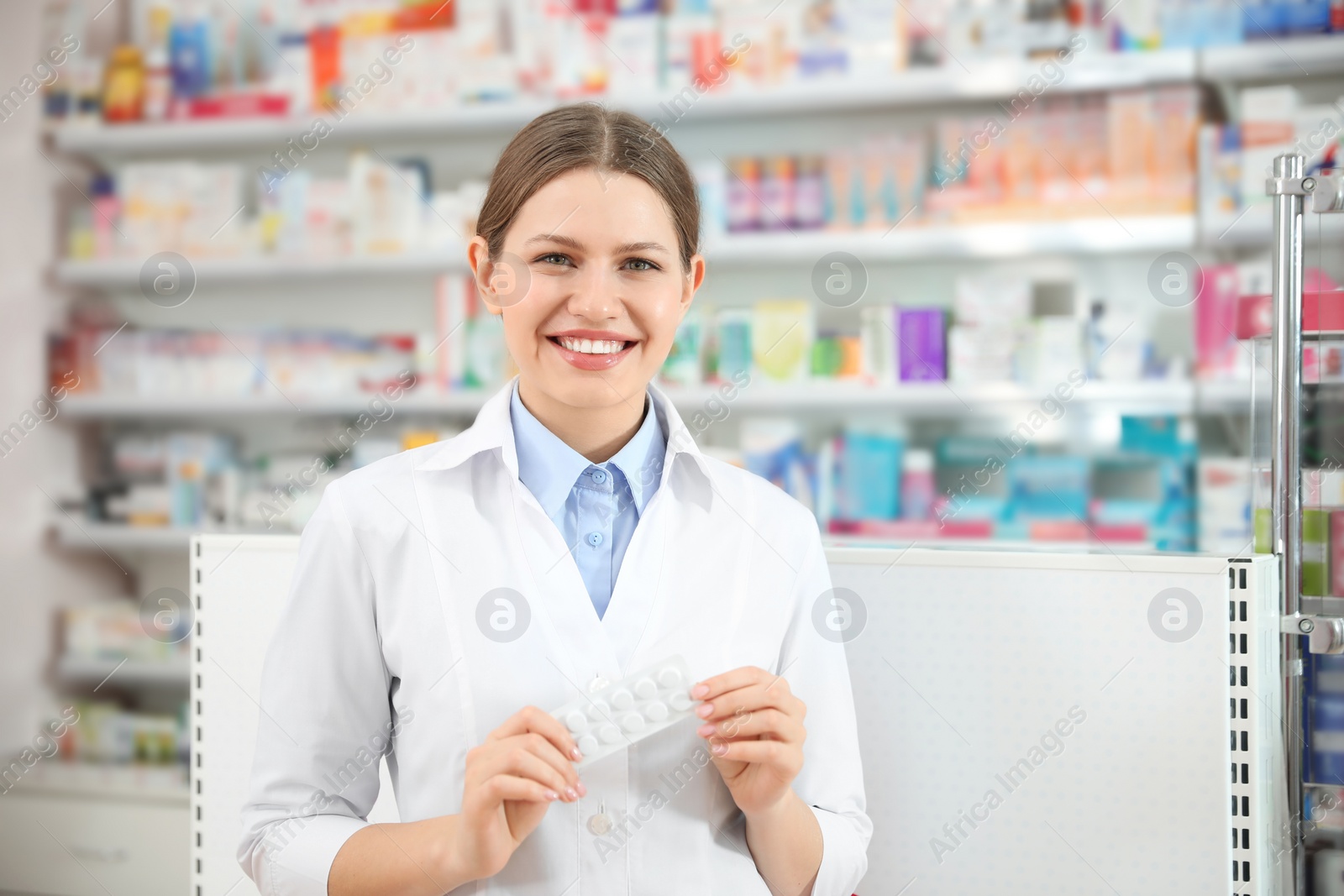 Photo of Professional pharmacist with pills in modern drugstore