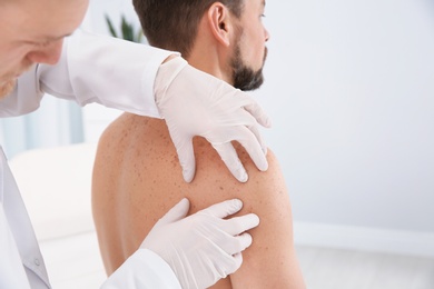 Photo of Dermatologist examining patient's birthmark in clinic