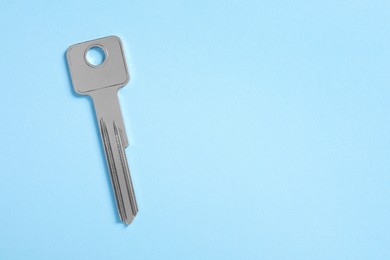 Photo of One key on light blue background, top view. Space for text