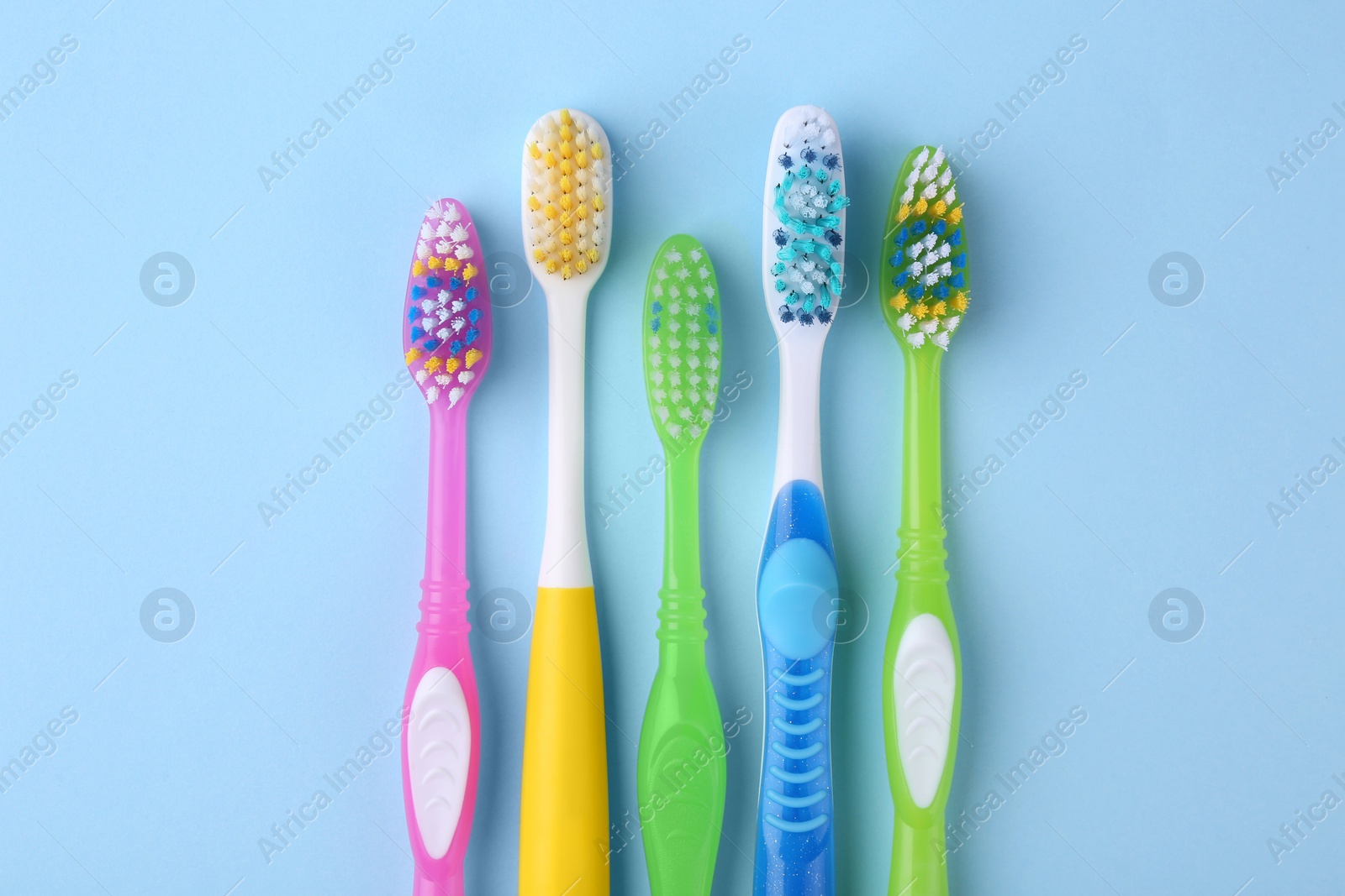 Photo of Many different toothbrushes on light blue background, flat lay