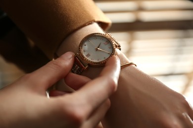 Photo of Woman wearing luxury wristwatch indoors, closeup of hand