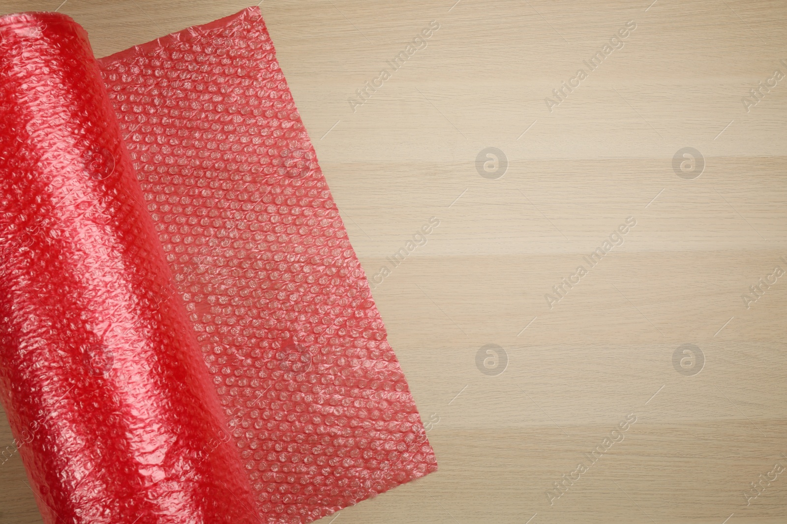 Photo of Bubble wrap roll on wooden background, top view. Space for text