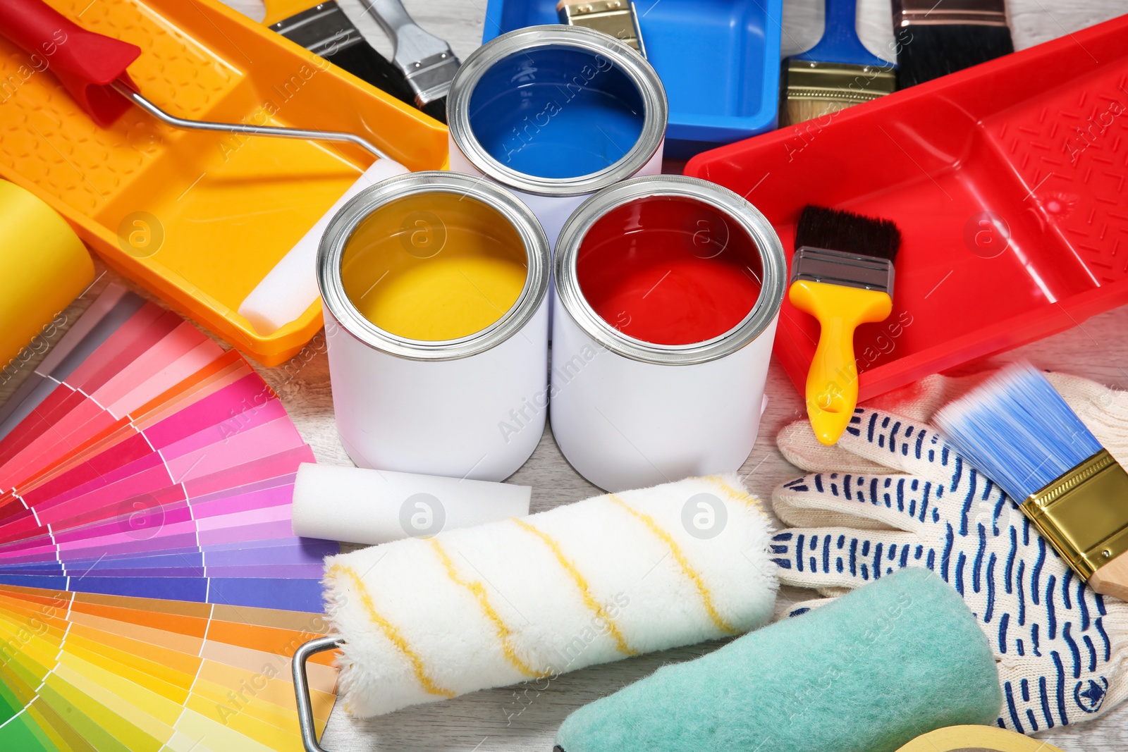 Photo of Cans of paint and decorator tools on wooden floor