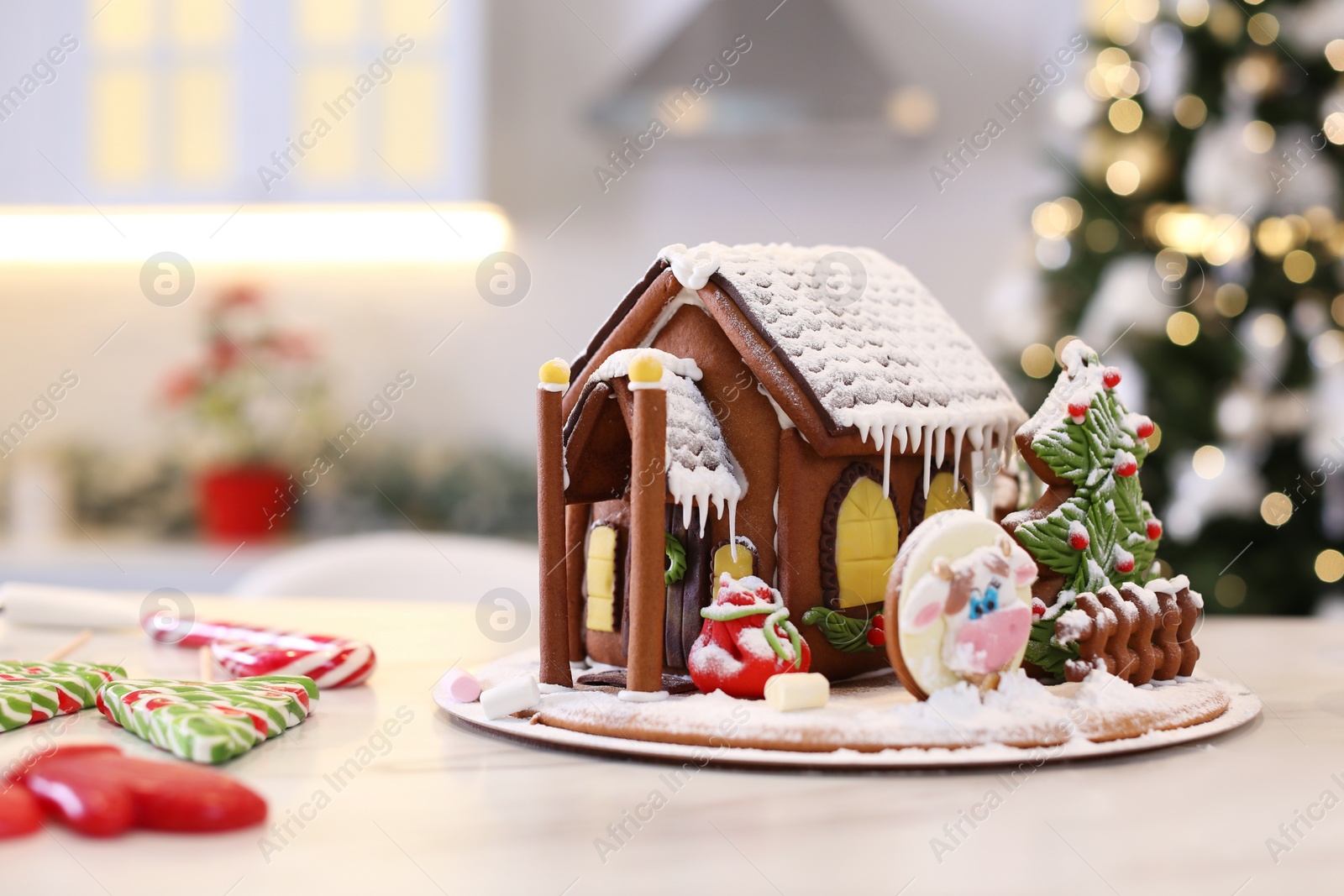 Photo of Beautiful gingerbread house decorated with icing on white table indoors