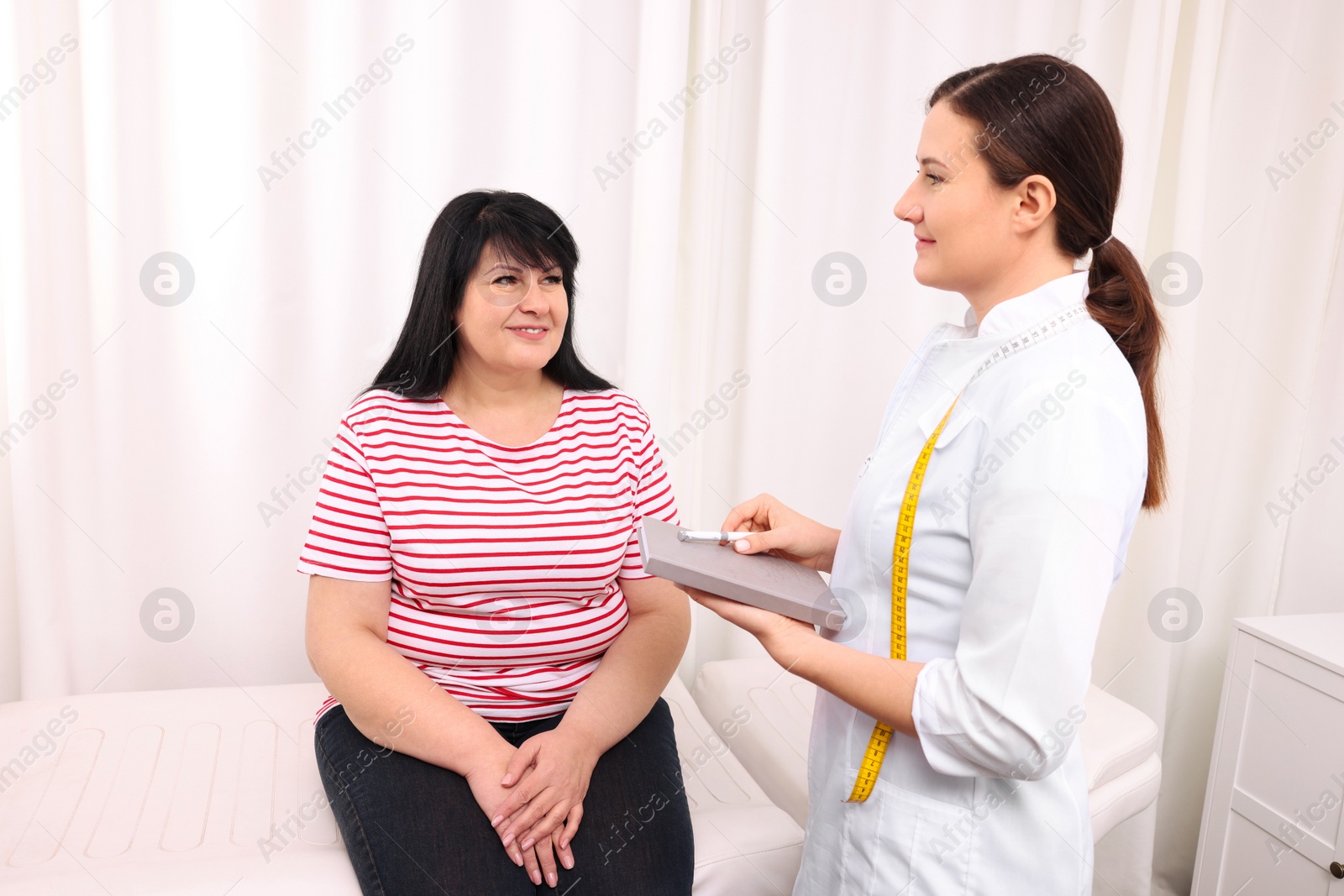 Photo of Overweight mature woman consulting with nutritionist in clinic
