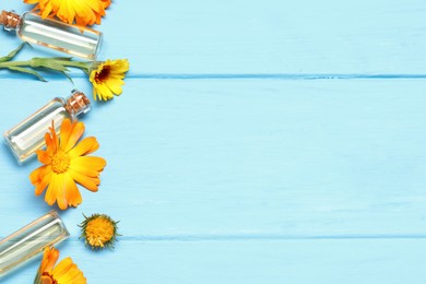 Photo of Bottles of essential oils and beautiful calendula flowers on light blue wooden table, flat lay. Space for text