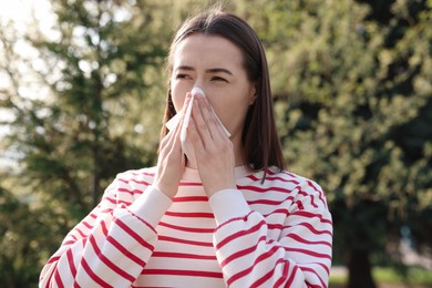 Photo of Woman with napkin suffering from seasonal allergy outdoors