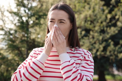 Woman with napkin suffering from seasonal allergy outdoors