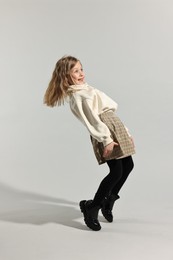 Fashion concept. Stylish girl posing on light grey background