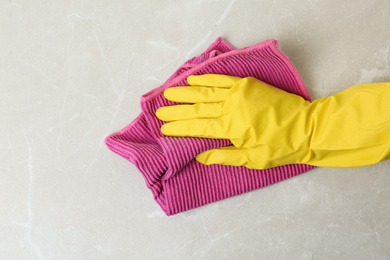 Photo of Person in gloves wiping grey marble table with rag, top view