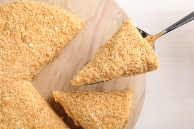 Taking piece of delicious Napoleon cake from table, top view