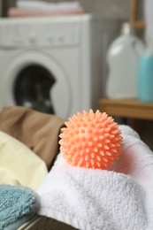 Photo of Orange dryer ball and towels near washing machine in laundry room, closeup