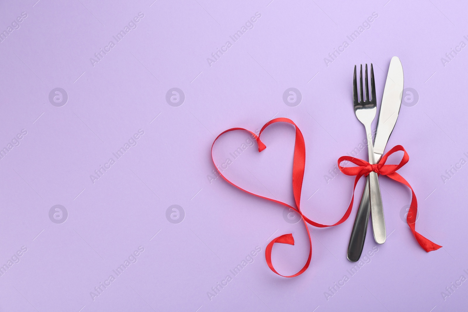 Photo of Beautiful cutlery set and red ribbon on violet background, flat lay with space for text. Valentine's Day dinner