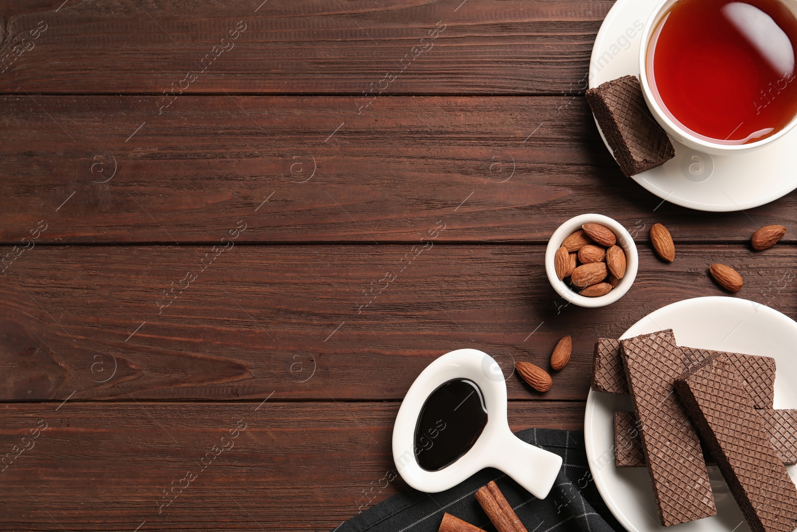 Photo of Flat lay composition with delicious chocolate wafers and cup of tea on wooden table. Space for text