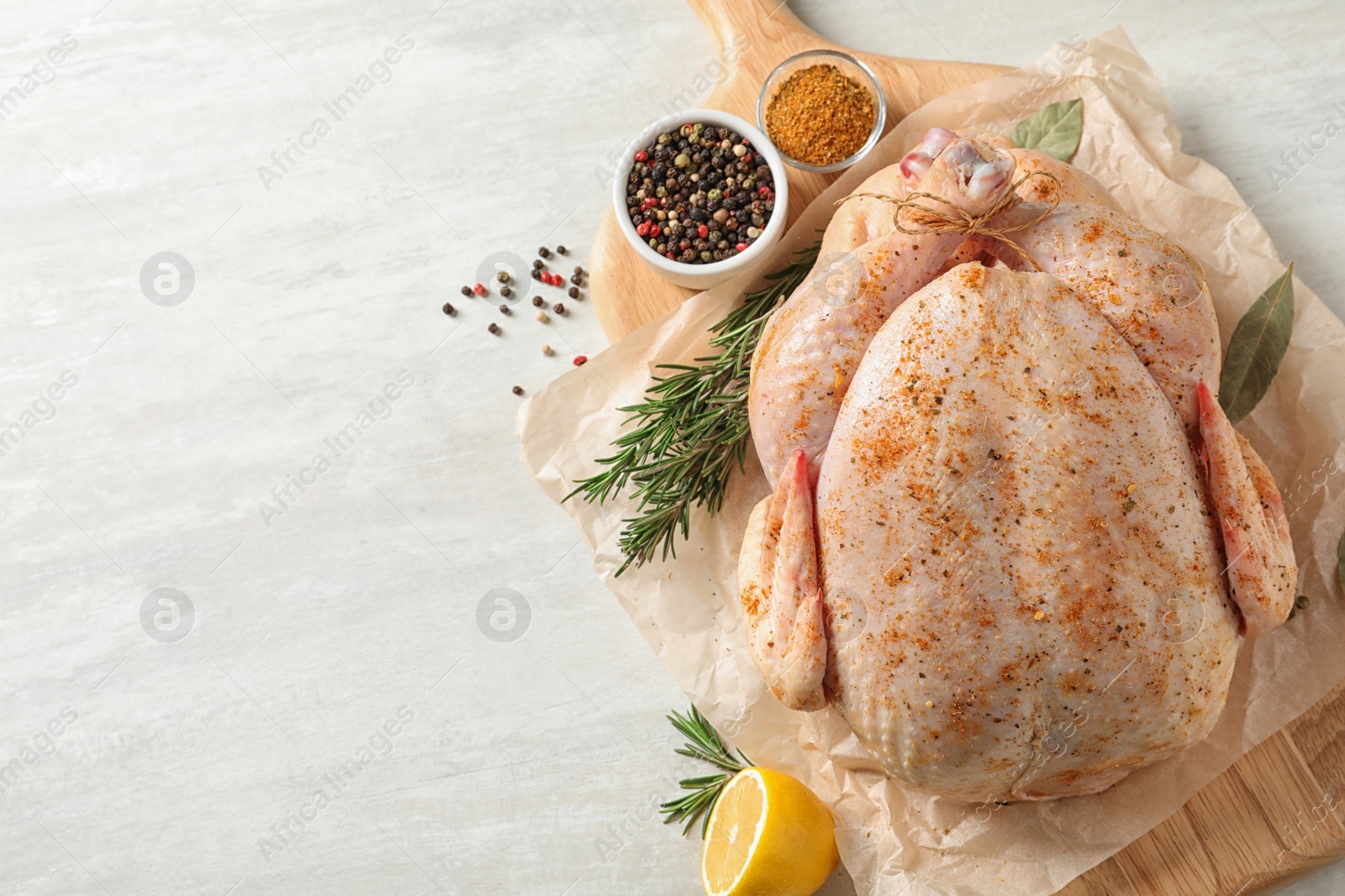 Photo of Board with raw spiced turkey and ingredients on light background, top view. Space for text