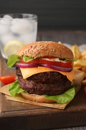 Photo of Tasty cheeseburger with patties, onion and tomato on wooden board, closeup