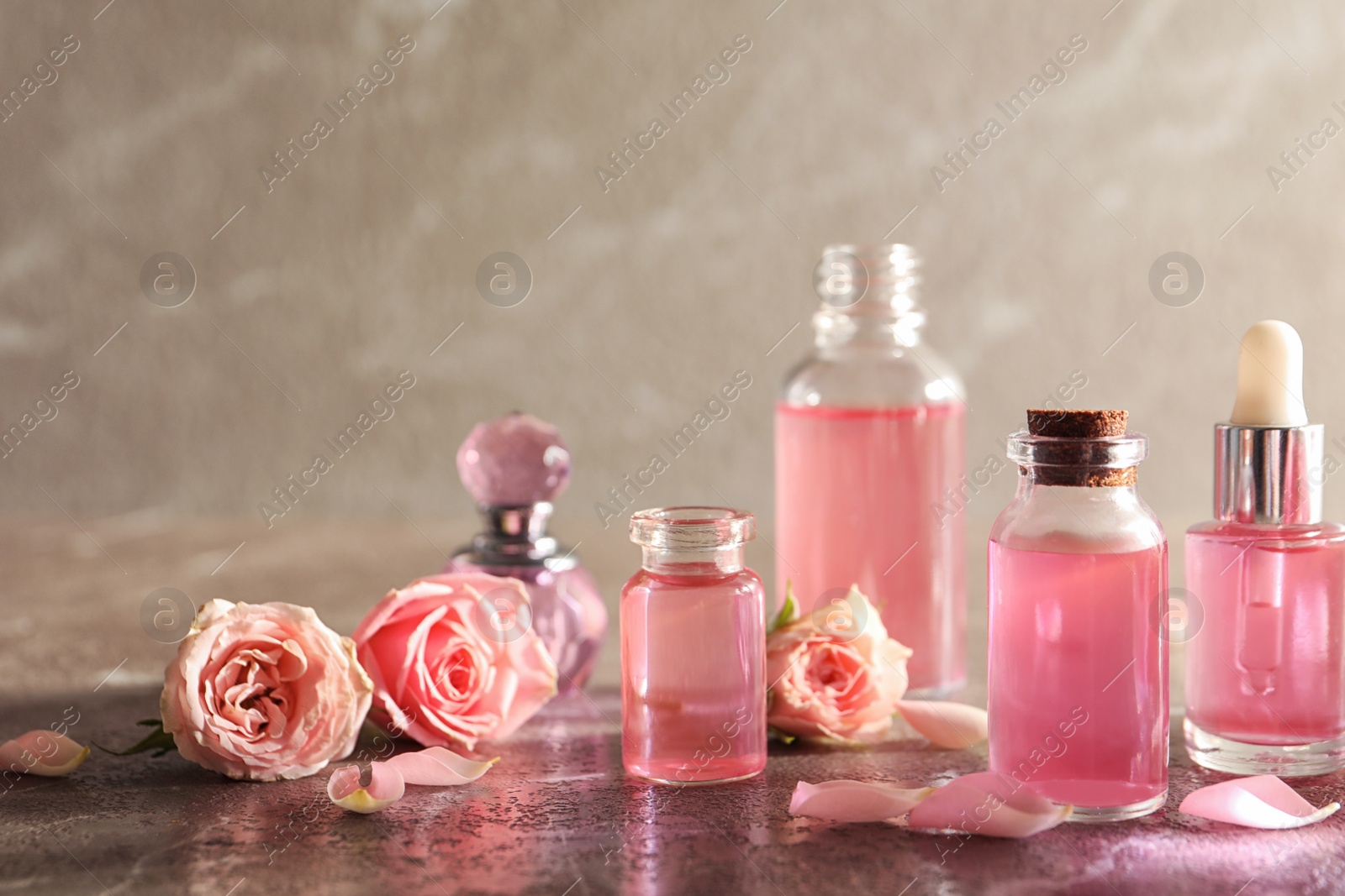 Photo of Composition with rose essential oil and flowers on table. Space for text