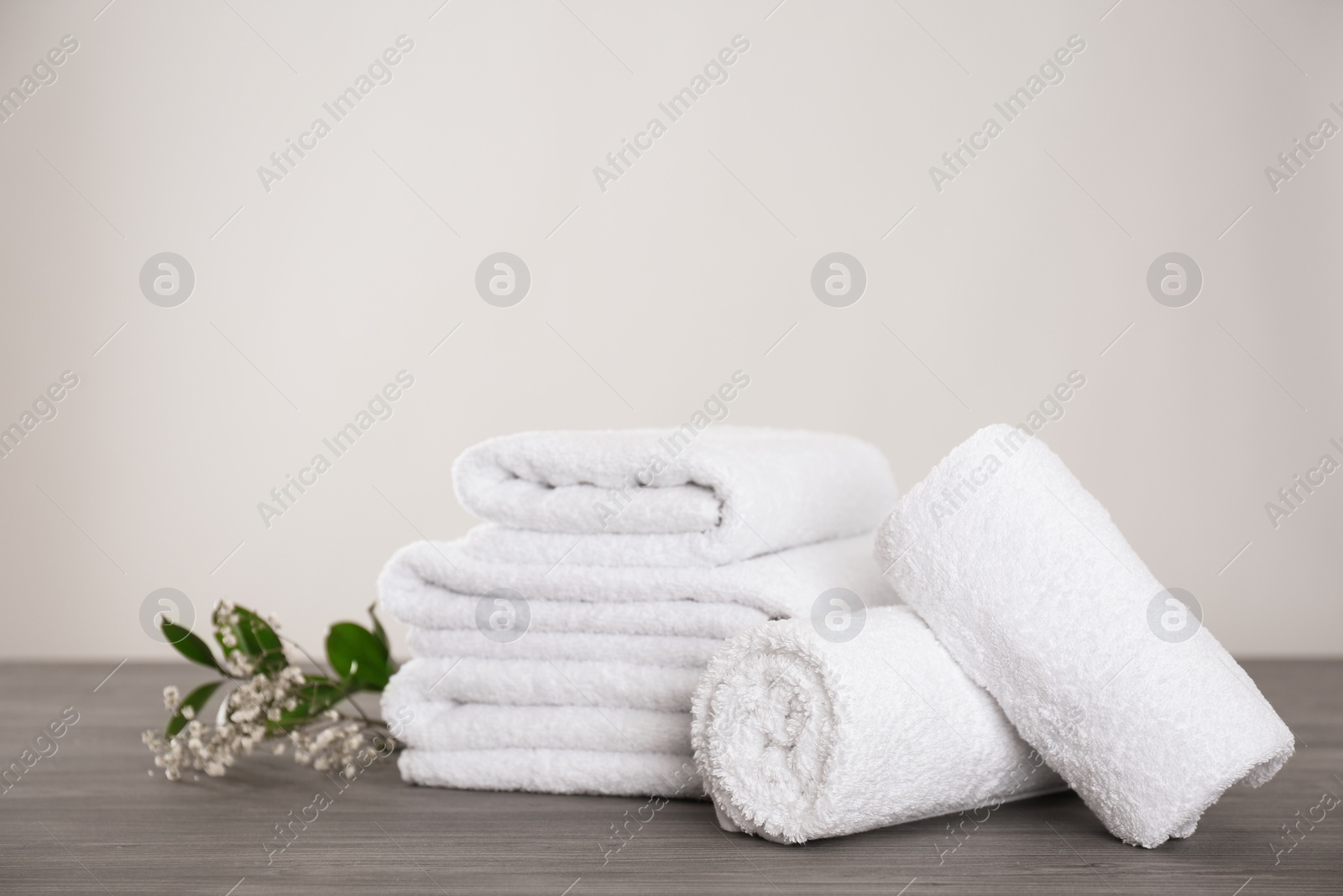 Photo of Fresh white towels and green plant on grey wooden table