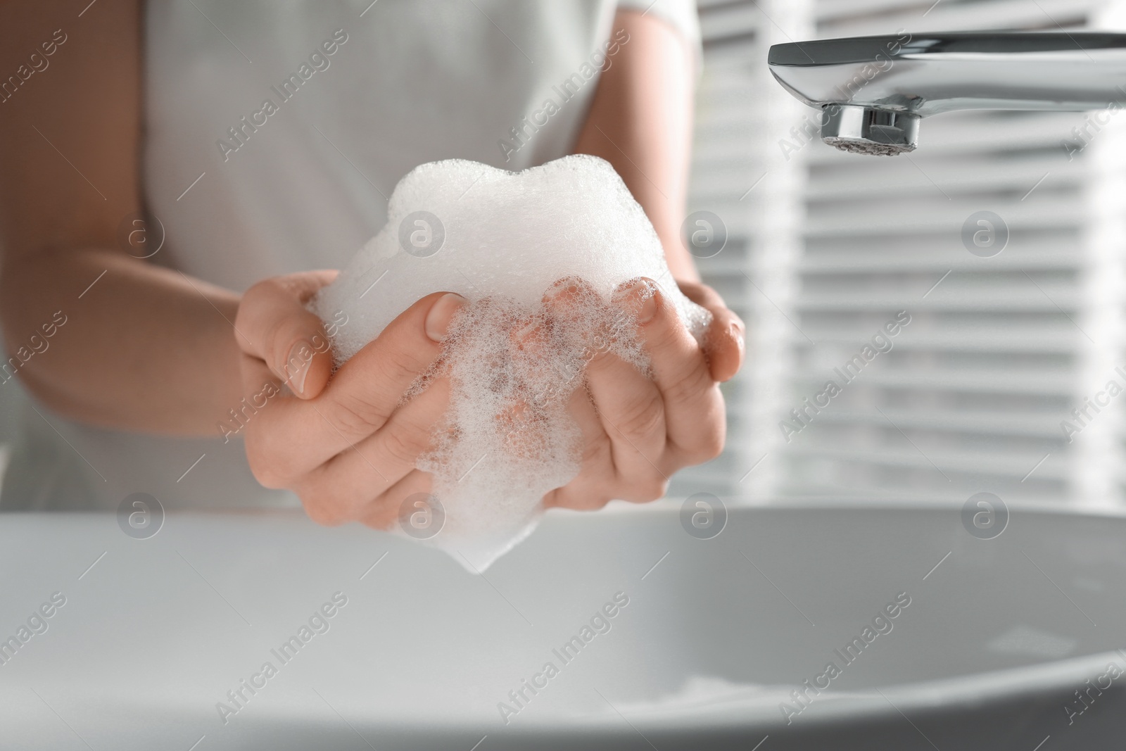 Photo of Woman washing hands with cleansing foam near sink in bathroom, closeup