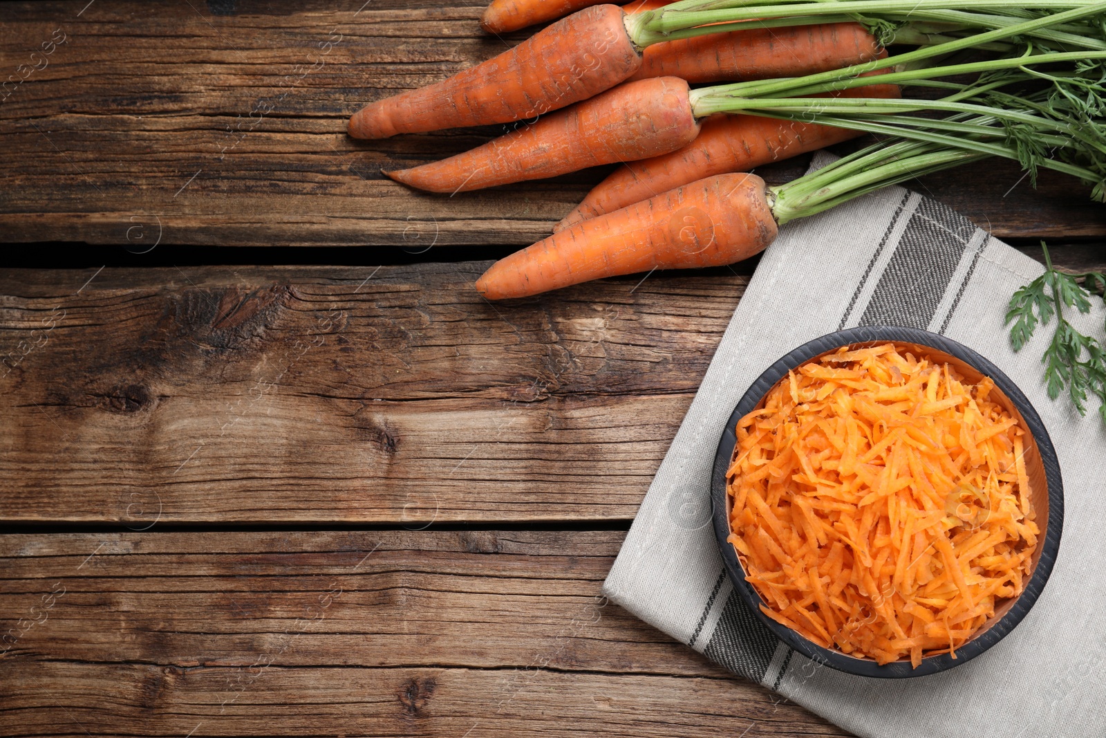 Photo of Flat lay composition with plate of grated carrot on wooden table. Space for text