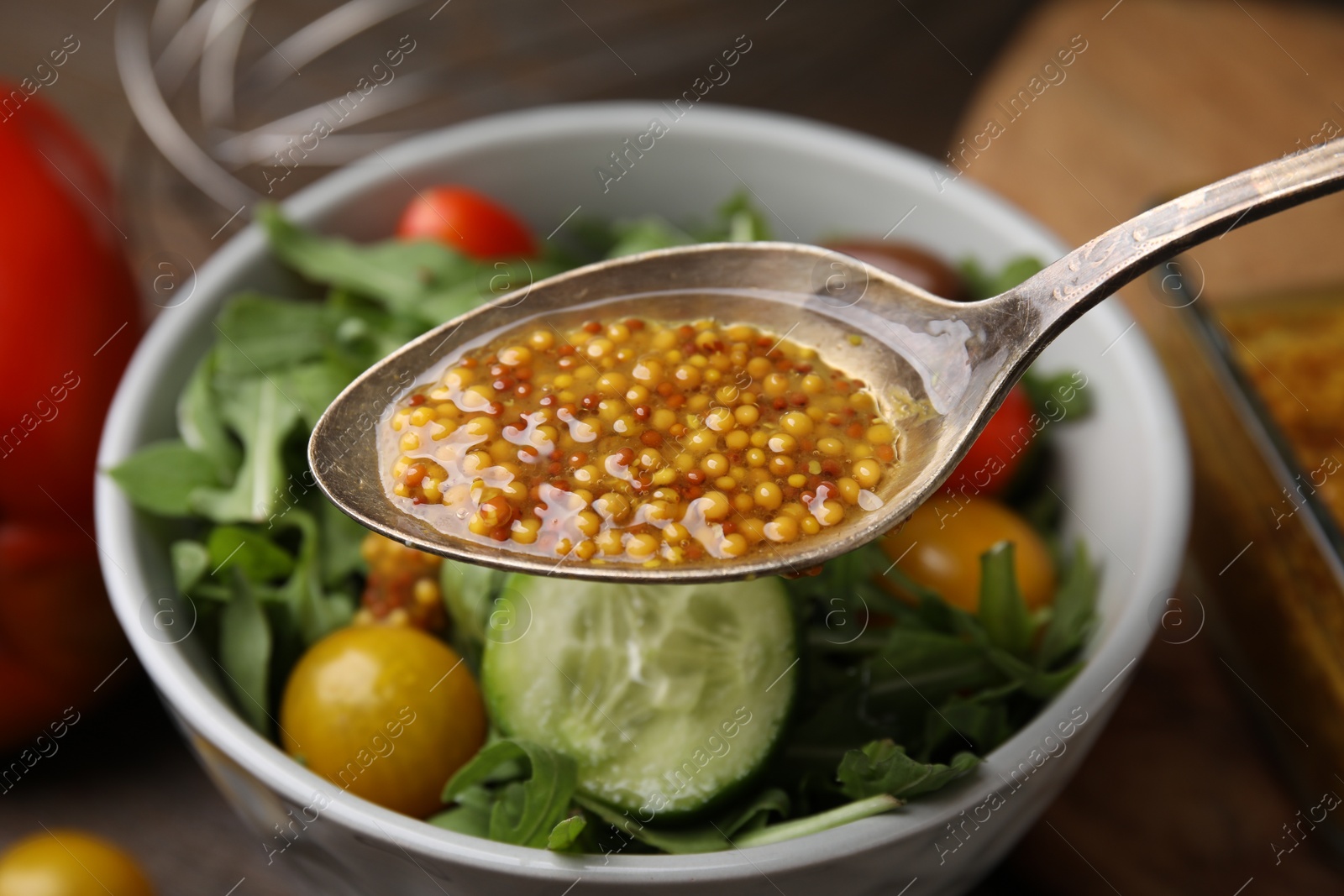 Photo of Spoon with tasty vinegar based sauce (Vinaigrette) over salad on table, closeup