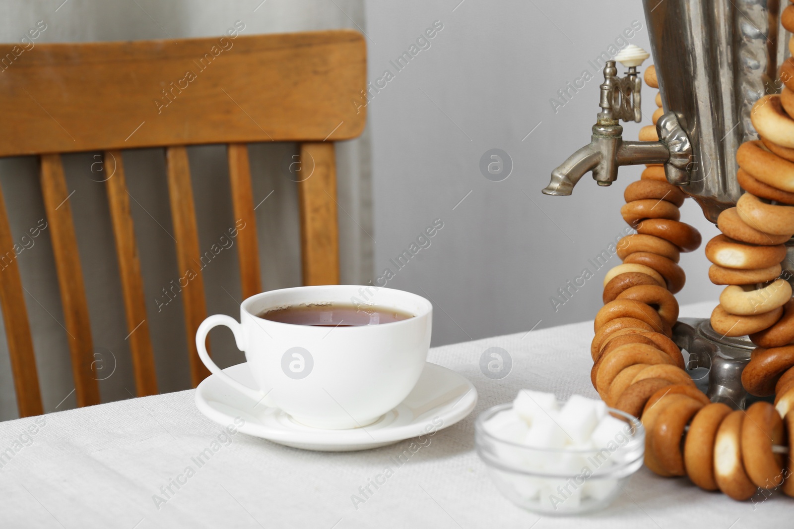 Photo of Vintage samovar, cup of hot drink and dry bagels served on table. Traditional Russian tea ceremony