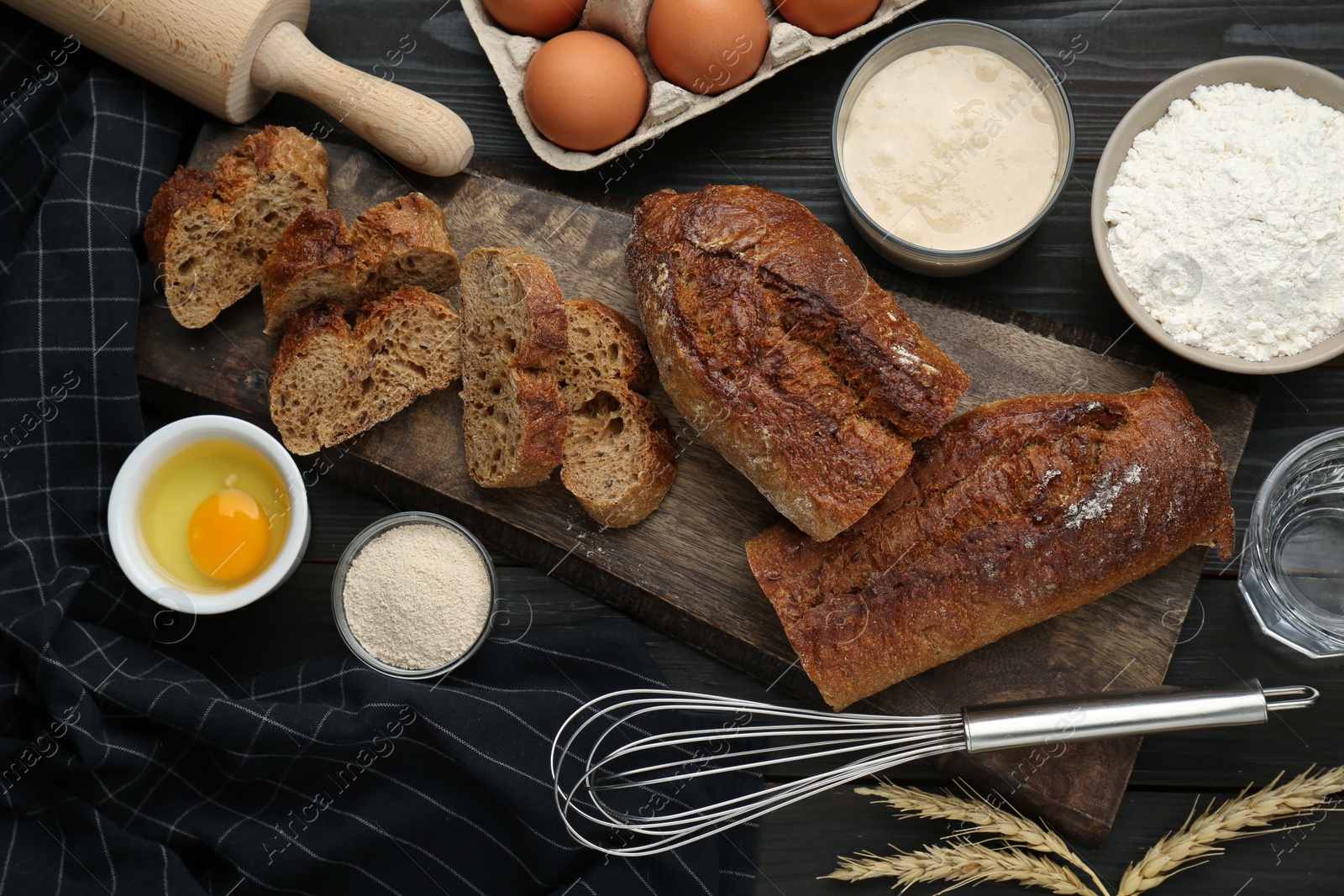 Photo of Flat lay composition with freshly baked bread and sourdough on wooden table