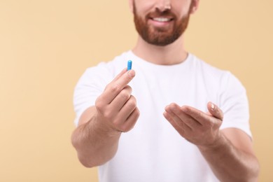 Photo of Man with pill on beige background, closeup. Space for text