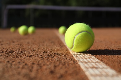 Photo of Bright yellow tennis ball on clay court