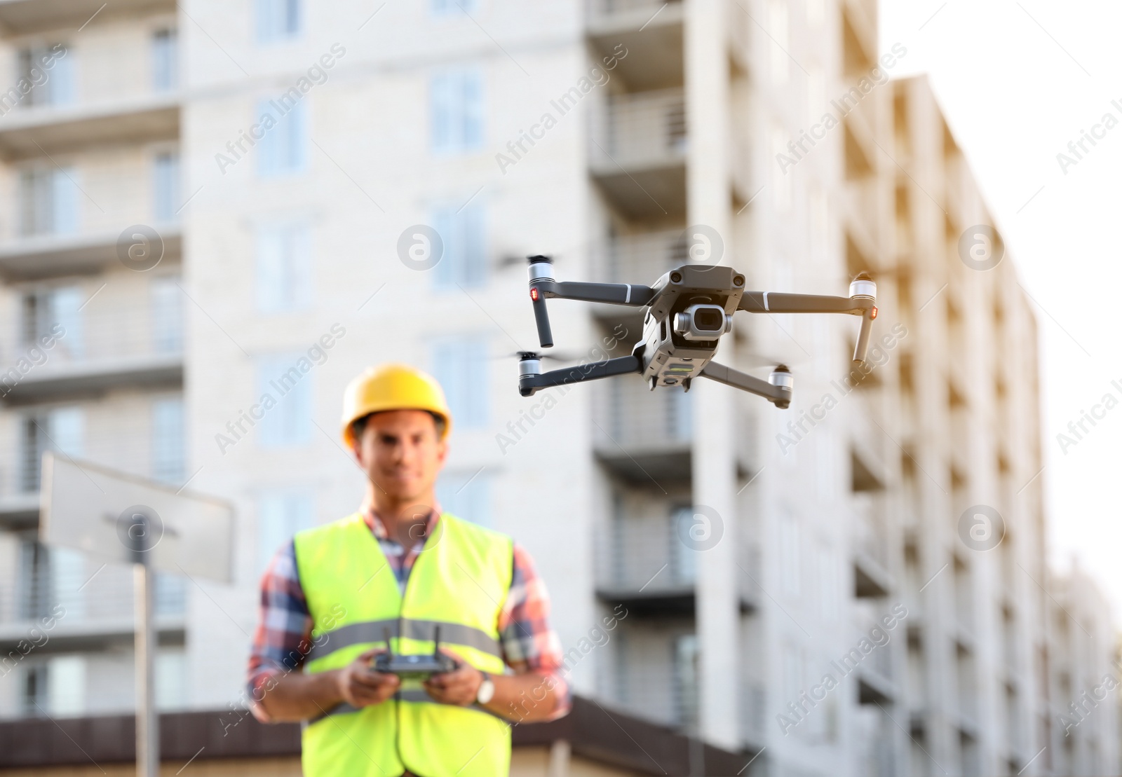 Photo of Builder operating drone with remote control at construction site, focus on quadcopter. Aerial survey