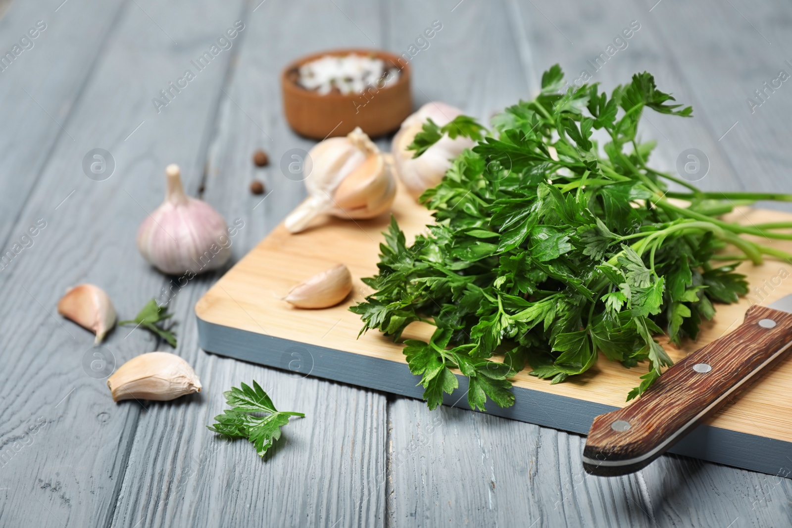 Photo of Board with fresh green parsley and garlic on table
