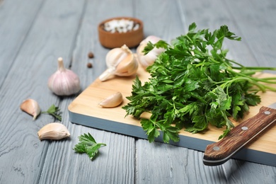 Board with fresh green parsley and garlic on table