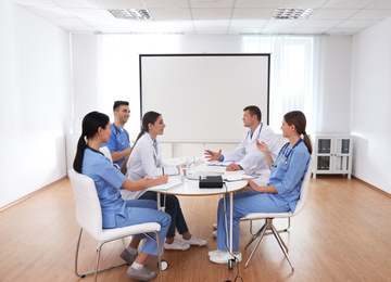 Photo of Team of doctors using video projector during conference indoors