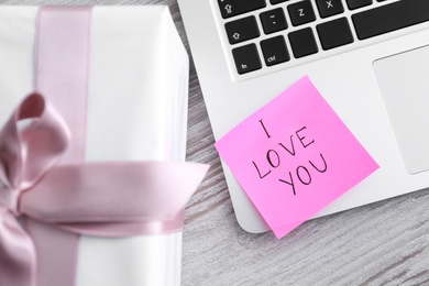 Photo of Memory sticker with phrase I Love You on laptop at table, flat lay. Valentine's Day celebration