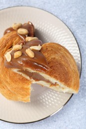 Photo of Supreme croissant with chocolate paste and nuts on grey table, top view. Tasty puff pastry