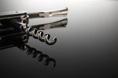 Photo of One corkscrew (sommelier knife) on mirror surface, closeup. Space for text