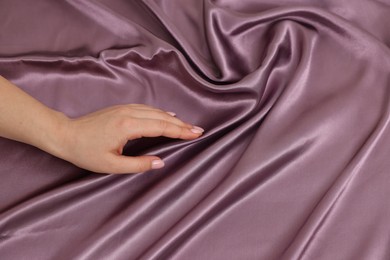 Woman touching smooth silky fabric, top view